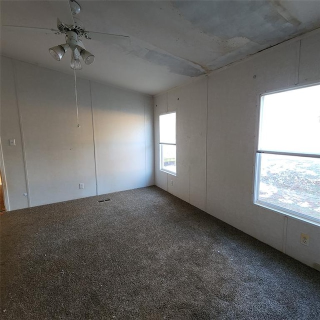 carpeted empty room featuring visible vents and ceiling fan