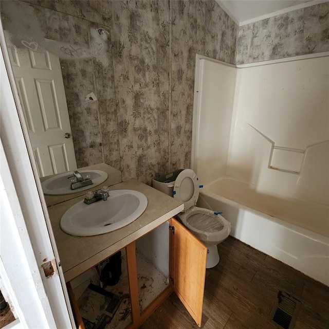 full bathroom featuring wallpapered walls, visible vents, a sink, and wood finished floors