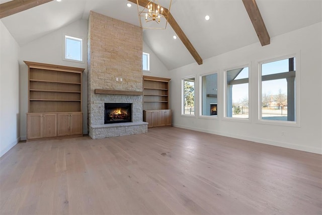 unfurnished living room featuring beam ceiling, high vaulted ceiling, a notable chandelier, a fireplace, and light hardwood / wood-style floors