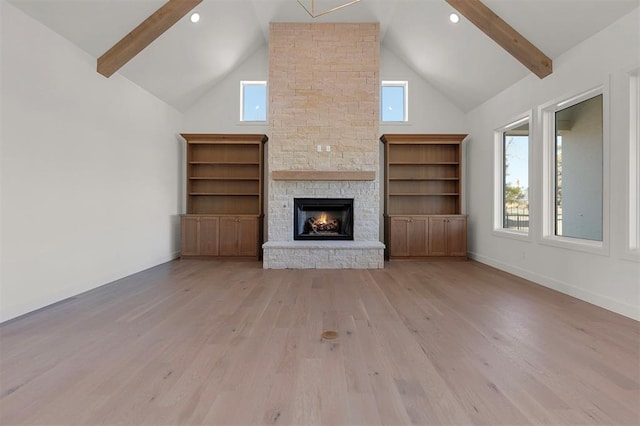 unfurnished living room featuring beam ceiling, a stone fireplace, light wood-type flooring, and high vaulted ceiling