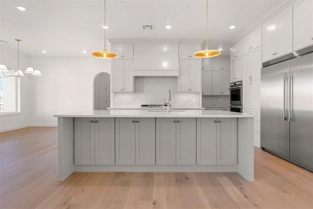 kitchen featuring appliances with stainless steel finishes, a kitchen island with sink, sink, pendant lighting, and white cabinetry