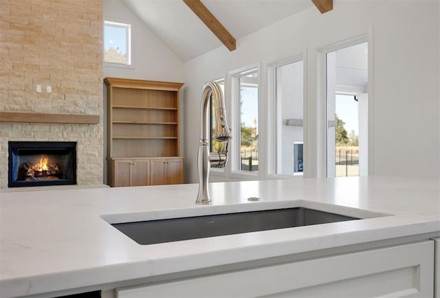 interior details with a fireplace, beam ceiling, and sink