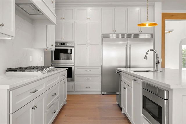 kitchen with light stone counters, hanging light fixtures, white cabinets, and stainless steel appliances