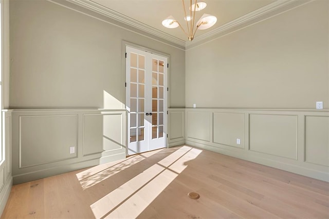 spare room with crown molding, french doors, a chandelier, and light wood-type flooring