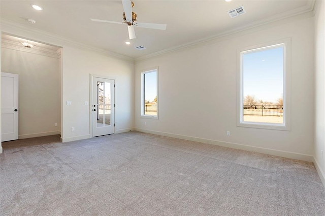 spare room featuring a wealth of natural light, crown molding, ceiling fan, and light colored carpet