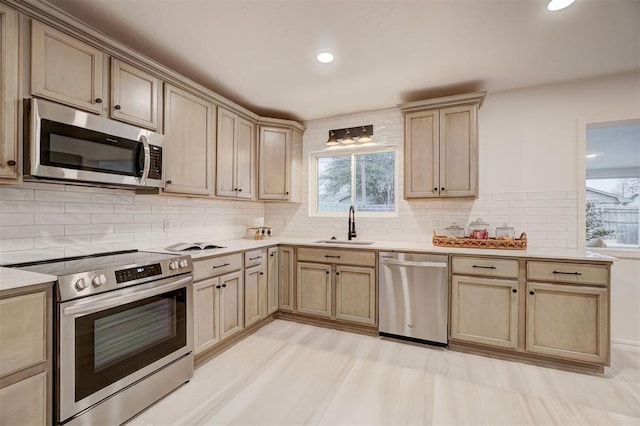 kitchen featuring sink, stainless steel appliances, light brown cabinetry, and tasteful backsplash