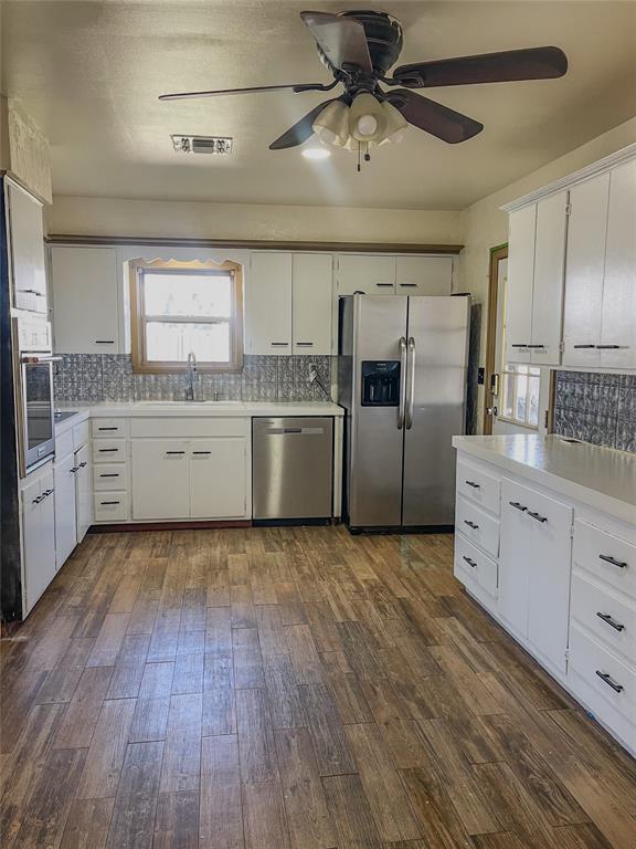 kitchen featuring appliances with stainless steel finishes, dark hardwood / wood-style floors, white cabinets, and sink