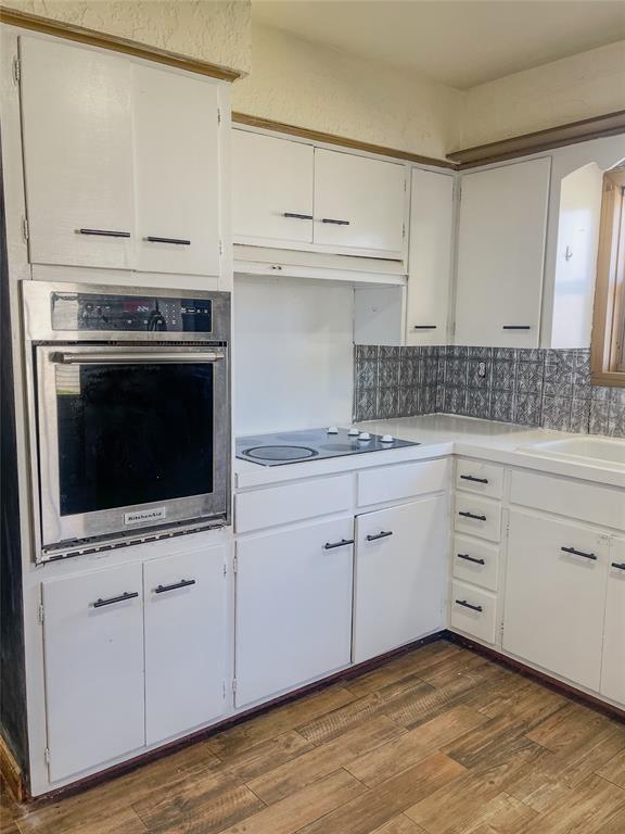 kitchen featuring stainless steel oven, black electric stovetop, white cabinets, and dark hardwood / wood-style flooring