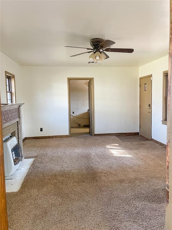 unfurnished living room with a fireplace, ceiling fan, light carpet, and heating unit