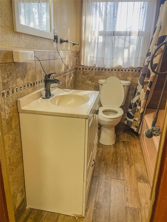 bathroom with toilet, wood-type flooring, vanity, and a healthy amount of sunlight