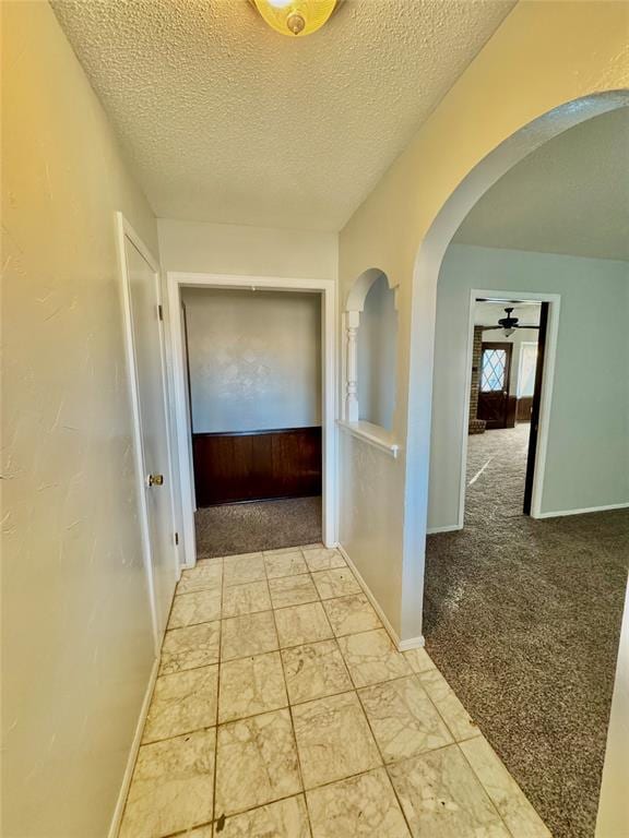 hallway featuring a textured ceiling and light carpet