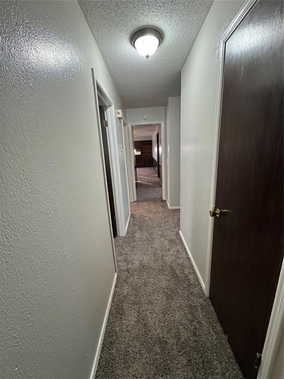 corridor featuring carpet floors and a textured ceiling