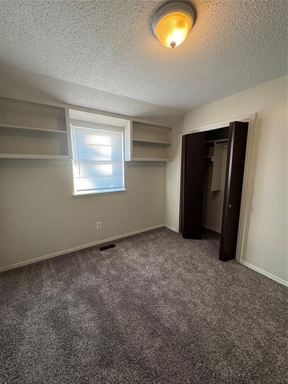 unfurnished bedroom with dark colored carpet, a textured ceiling, and a closet