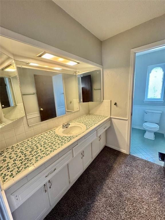 bathroom featuring decorative backsplash, toilet, and vanity