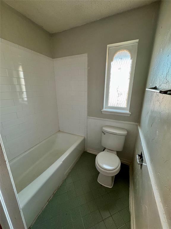 bathroom featuring a washtub, a textured ceiling, and toilet