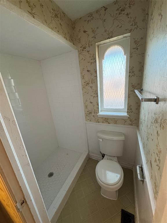 bathroom featuring a shower, tile patterned floors, and toilet