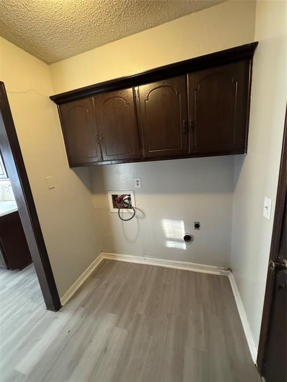 laundry area with cabinets, electric dryer hookup, light hardwood / wood-style flooring, hookup for a washing machine, and a textured ceiling