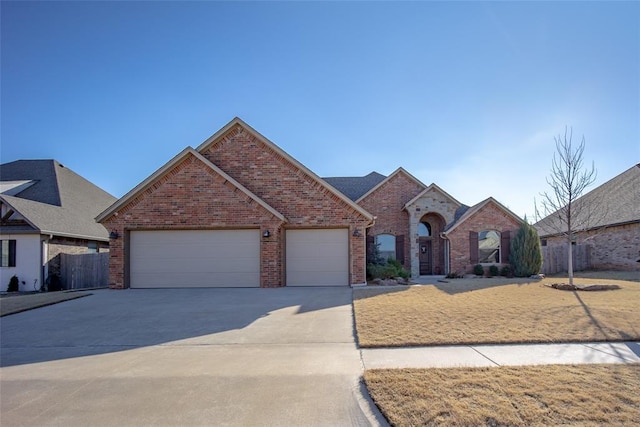 view of front of home featuring driveway, brick siding, an attached garage, and fence