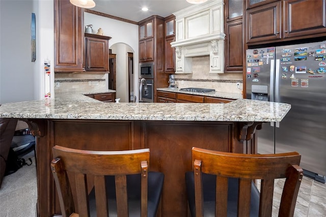 kitchen with backsplash, light stone countertops, kitchen peninsula, and stainless steel appliances