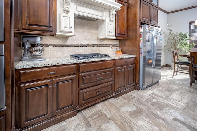 kitchen featuring backsplash, light stone counters, ornamental molding, and stainless steel appliances