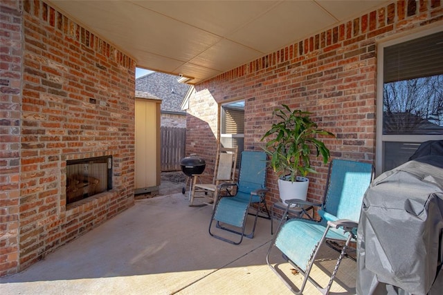 view of patio with an outdoor brick fireplace and grilling area