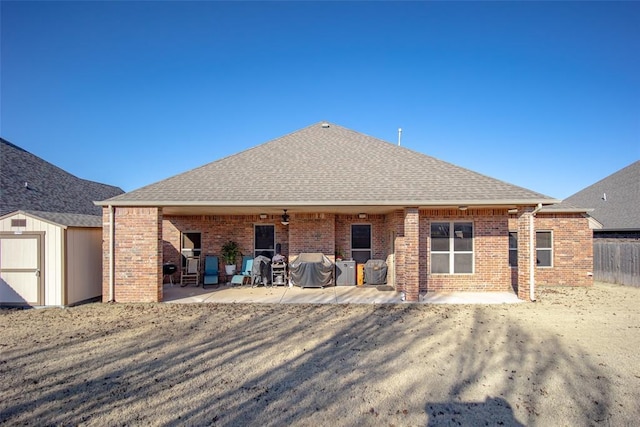 rear view of property featuring a patio and a storage unit