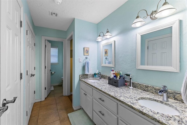 bathroom featuring tile patterned floors, vanity, a textured ceiling, and toilet