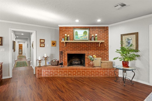 living room featuring hardwood / wood-style flooring, ornamental molding, a textured ceiling, and a brick fireplace