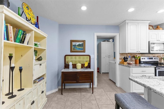 kitchen featuring backsplash, white cabinetry, light tile patterned flooring, and appliances with stainless steel finishes