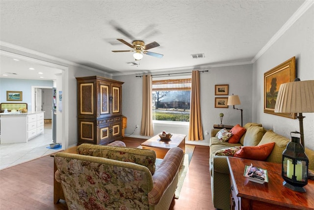 living room featuring a textured ceiling, light hardwood / wood-style flooring, ceiling fan, and ornamental molding