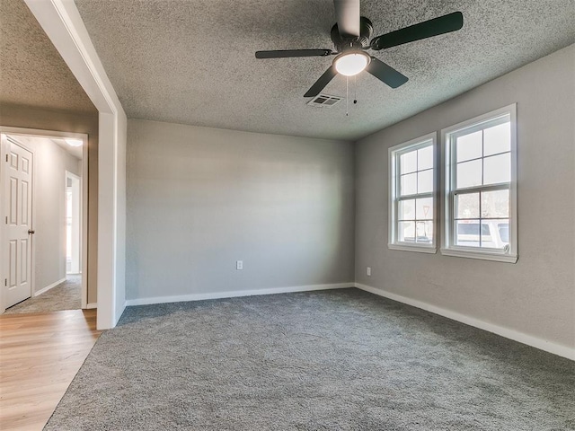 carpeted empty room with ceiling fan and a textured ceiling