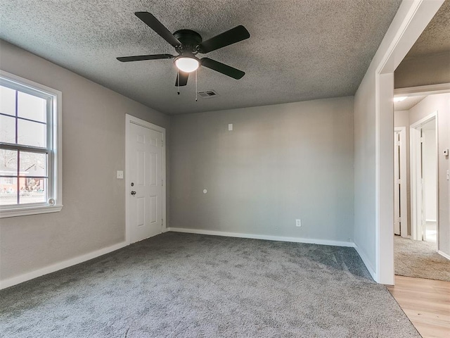 carpeted empty room with ceiling fan and a textured ceiling