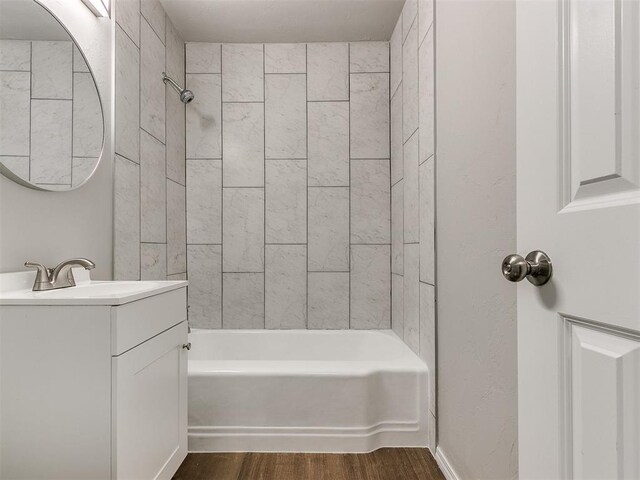 bathroom with hardwood / wood-style floors, vanity, and tiled shower / bath