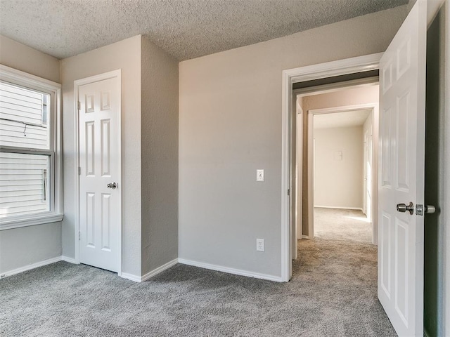 unfurnished bedroom with a textured ceiling and light colored carpet