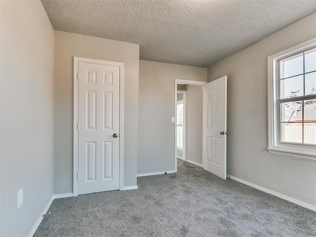 unfurnished bedroom with light carpet, a textured ceiling, and multiple windows