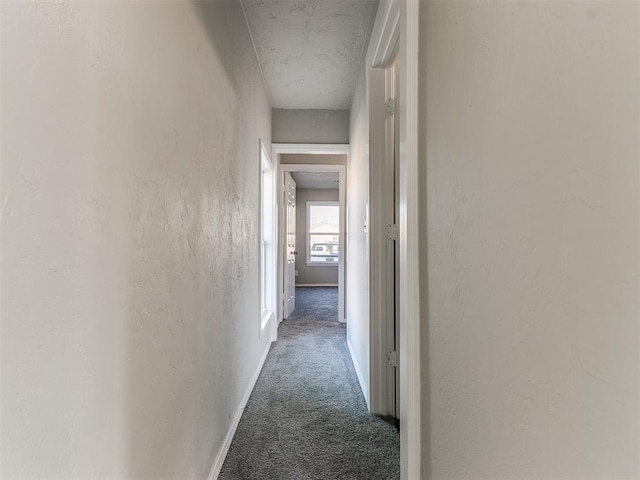 hallway with dark colored carpet and a textured ceiling