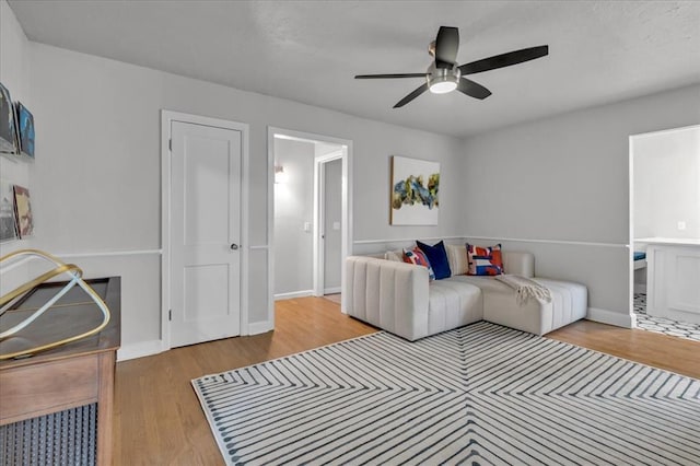 living area featuring baseboards, a ceiling fan, and wood finished floors