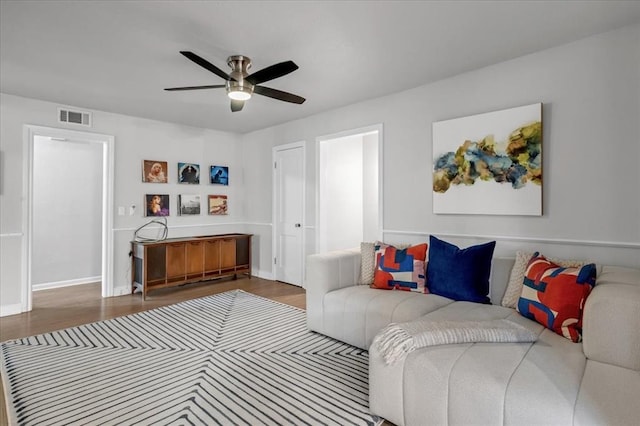 living room with baseboards, ceiling fan, visible vents, and wood finished floors