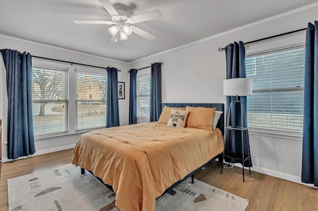 bedroom with ceiling fan, crown molding, light hardwood / wood-style flooring, and multiple windows