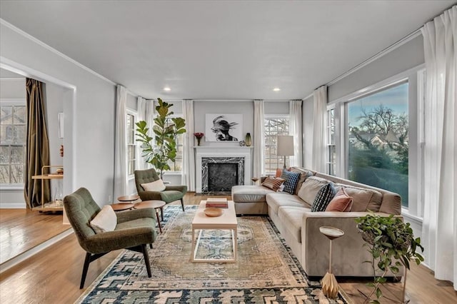 living room featuring a high end fireplace, crown molding, and light wood-type flooring