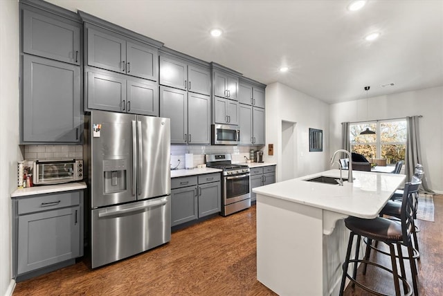 kitchen with backsplash, sink, a breakfast bar area, gray cabinets, and stainless steel appliances