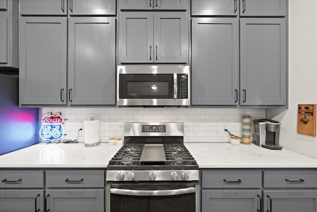 kitchen with decorative backsplash, appliances with stainless steel finishes, and gray cabinets