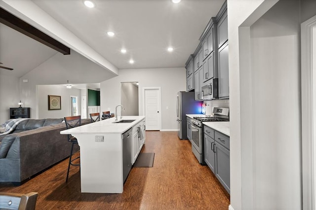 kitchen featuring ceiling fan, sink, an island with sink, a breakfast bar, and appliances with stainless steel finishes