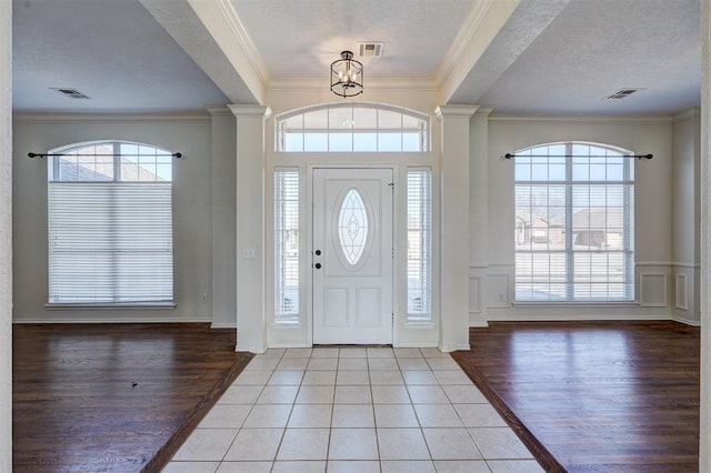 foyer featuring light tile patterned floors, a healthy amount of sunlight, a textured ceiling, and a notable chandelier