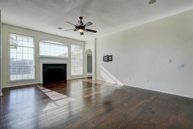 unfurnished living room with a high end fireplace, a textured ceiling, dark hardwood / wood-style floors, and ceiling fan