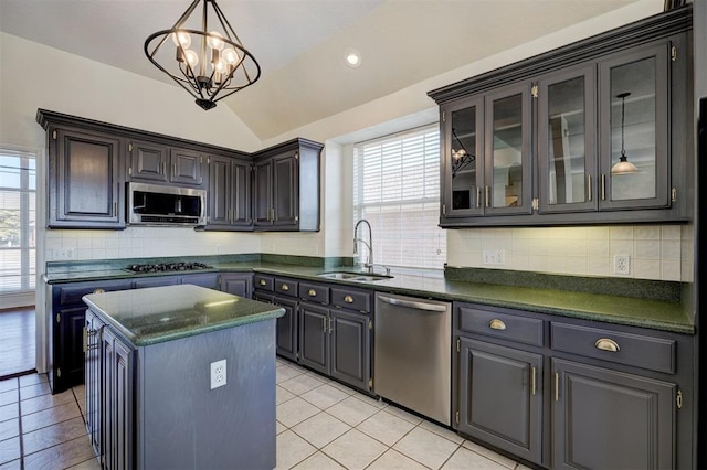 kitchen featuring appliances with stainless steel finishes, backsplash, vaulted ceiling, sink, and a kitchen island