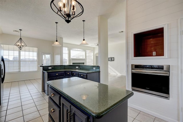 kitchen featuring a center island, oven, decorative light fixtures, light tile patterned floors, and ceiling fan with notable chandelier