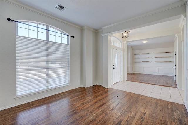 entryway with hardwood / wood-style flooring, crown molding, and an inviting chandelier