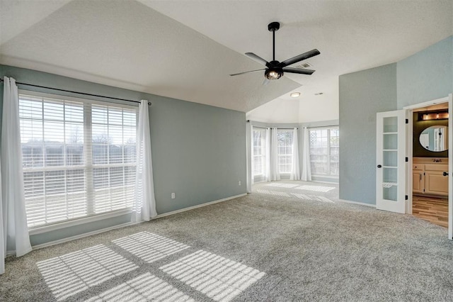 unfurnished living room featuring ceiling fan, french doors, light carpet, and vaulted ceiling