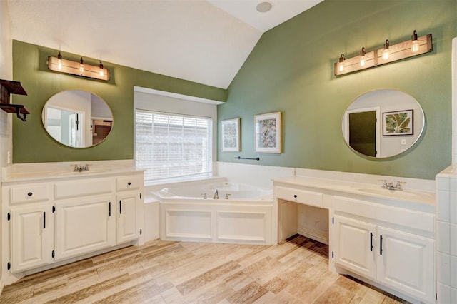 bathroom with hardwood / wood-style floors, vanity, vaulted ceiling, and a tub